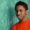 This is a photo of a male student standing in front of a chalkboard.