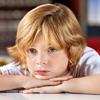 This is a photo of a boy with his head resting on his hands.